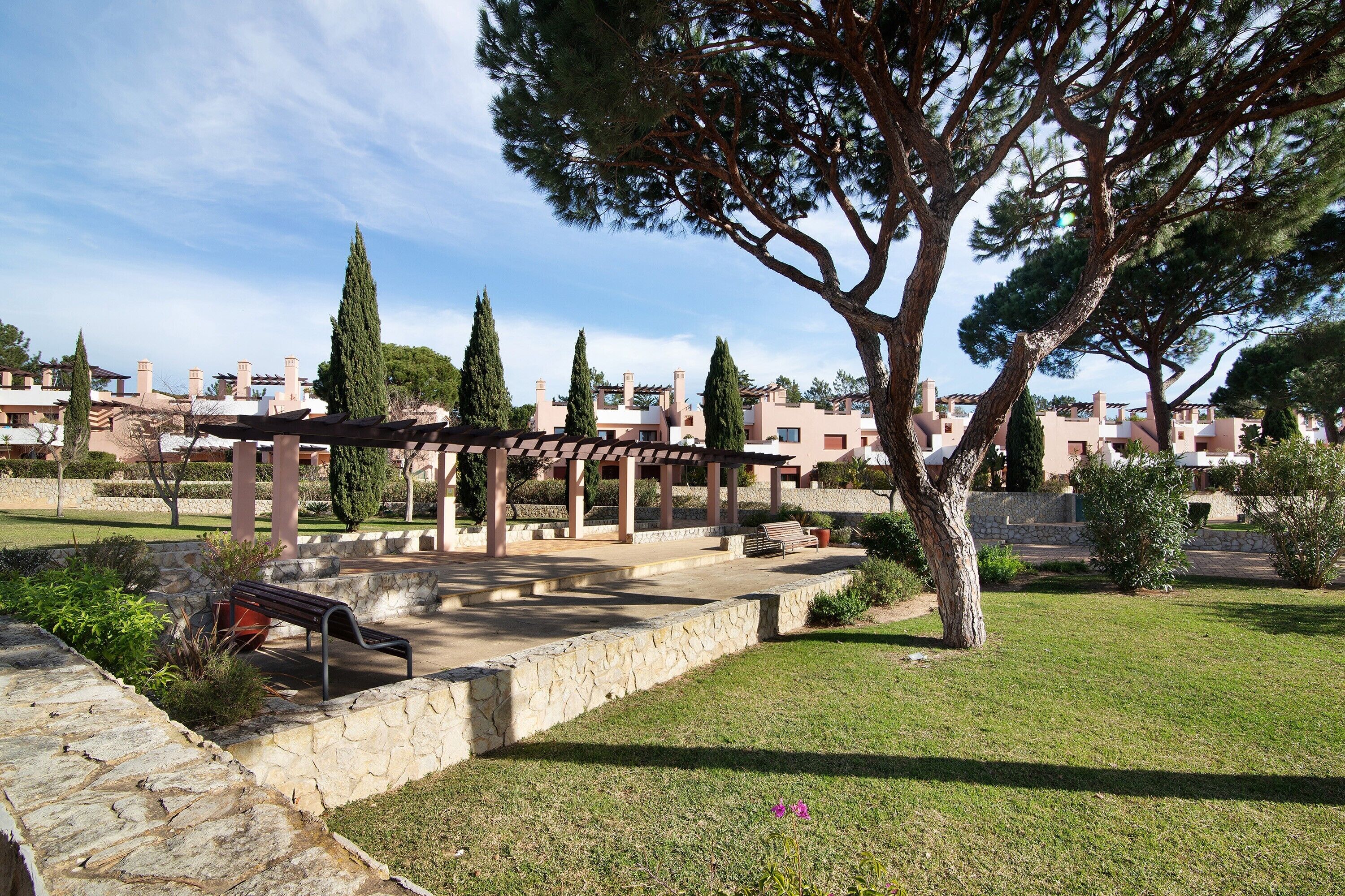 Un parc doté d’une pergola, de murs en pierre et d’une pelouse.