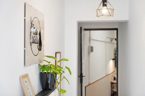 A hallway with a framed sign, a potted plant, and a hanging light fixture.
