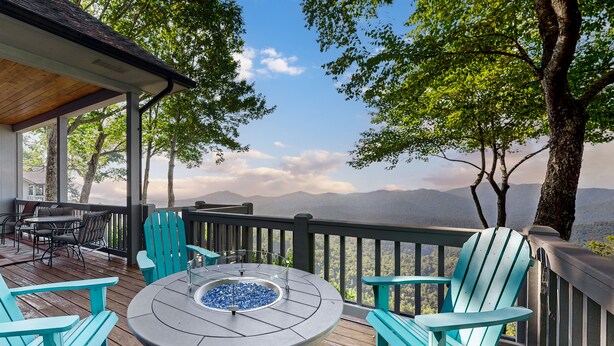 Una terraza con una mesa redonda y sillas, con vistas a un paisaje montañoso.