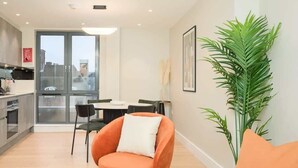 A modern living room with a dining area, a large window, and a potted plant. - Modern Marylebone apartment with balcony (London)
