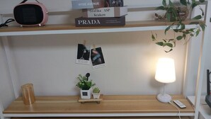 En hylde med bøger, en lille plante, en lampe og en kop.