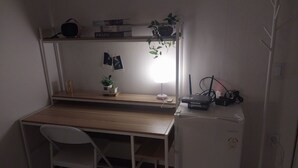 Et lille arbejdsområde med et skrivebord, en stol og et hvidt skab.