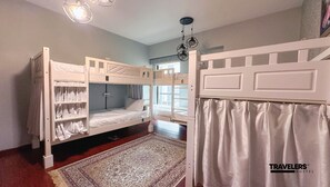 A dormitory room with bunk beds, a window with curtains, a patterned rug, and a ceiling light fixture. - Travelers Dubai Marina Hostel (Dubai)