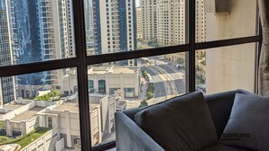A modern hotel room with a large window offering a view of high-rise buildings and a curved road. - Travelers Dubai Marina Hostel (Dubai)