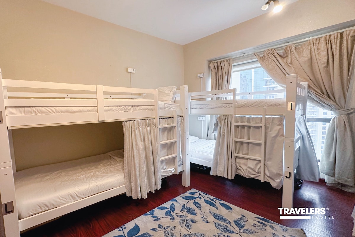 Une chambre avec un lit superposé, une fenêtre, des rideaux et un tapis à motifs.