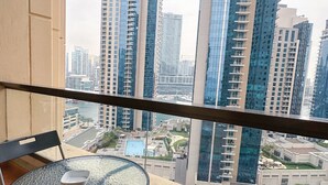 A balcony with a table and chairs, overlooking a cityscape with tall buildings. - Travelers Dubai Marina Hostel (Dubai)