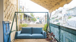 En balkon med en blå sofa, træloft og udsigt over bybilledet.