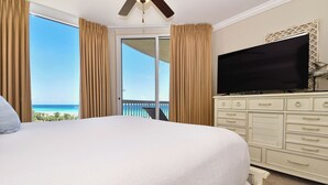 Ein Hotelzimmer mit einem großen Bett, einem Fernseher und Blick auf den Ozean.