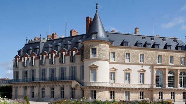 Un grand bâtiment historique doté de nombreuses tours et d’une façade symétrique.