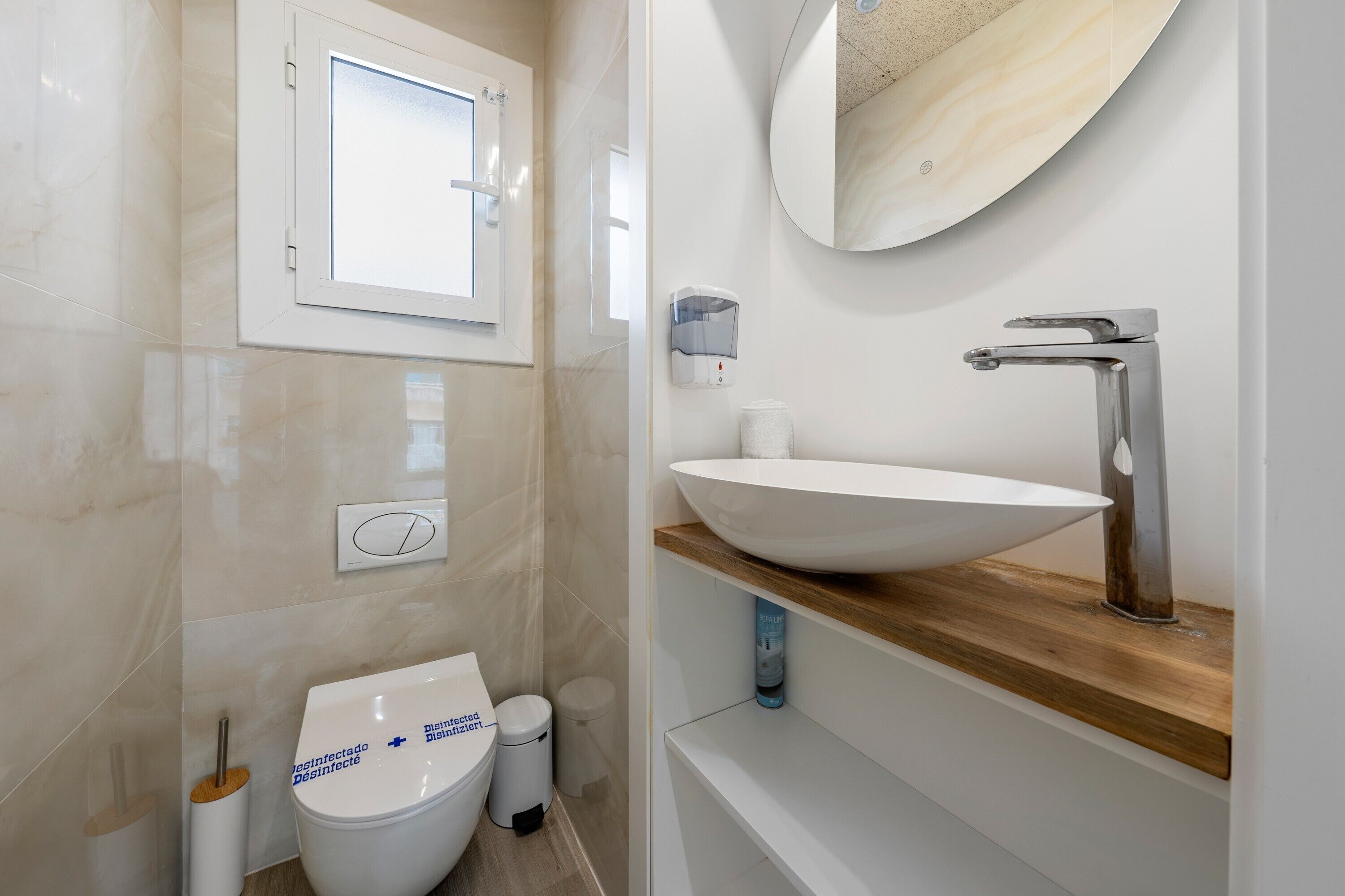 Un baño moderno con inodoro, bidé, lavamanos, espejo y ventana.