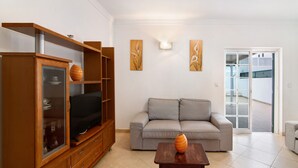 A living room with a sofa, TV, wooden cabinet, and artwork on the wall. - Holiday Home 'Moradia Altura' with Private Terrace and Balcony (Altura)