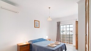A bedroom with a bed, bedside table, lamp, and a view through a window. - Holiday Home 'Moradia Altura' with Private Terrace and Balcony (Altura)