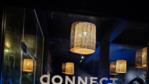 A co-working space with glass walls, white furniture, and woven pendant lights. - Sugar Hostel Weligama  (Weligama)