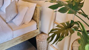 A cozy room with a white sofa, a large potted plant, and a poster on the wall. - Sugar Hostel Weligama  (Weligama)