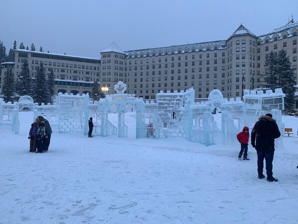 A snow-covered outdoor area with ice sculptures and a large building in the background.