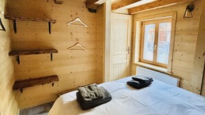Een houten kamer met een bed, een raam en houten planken.