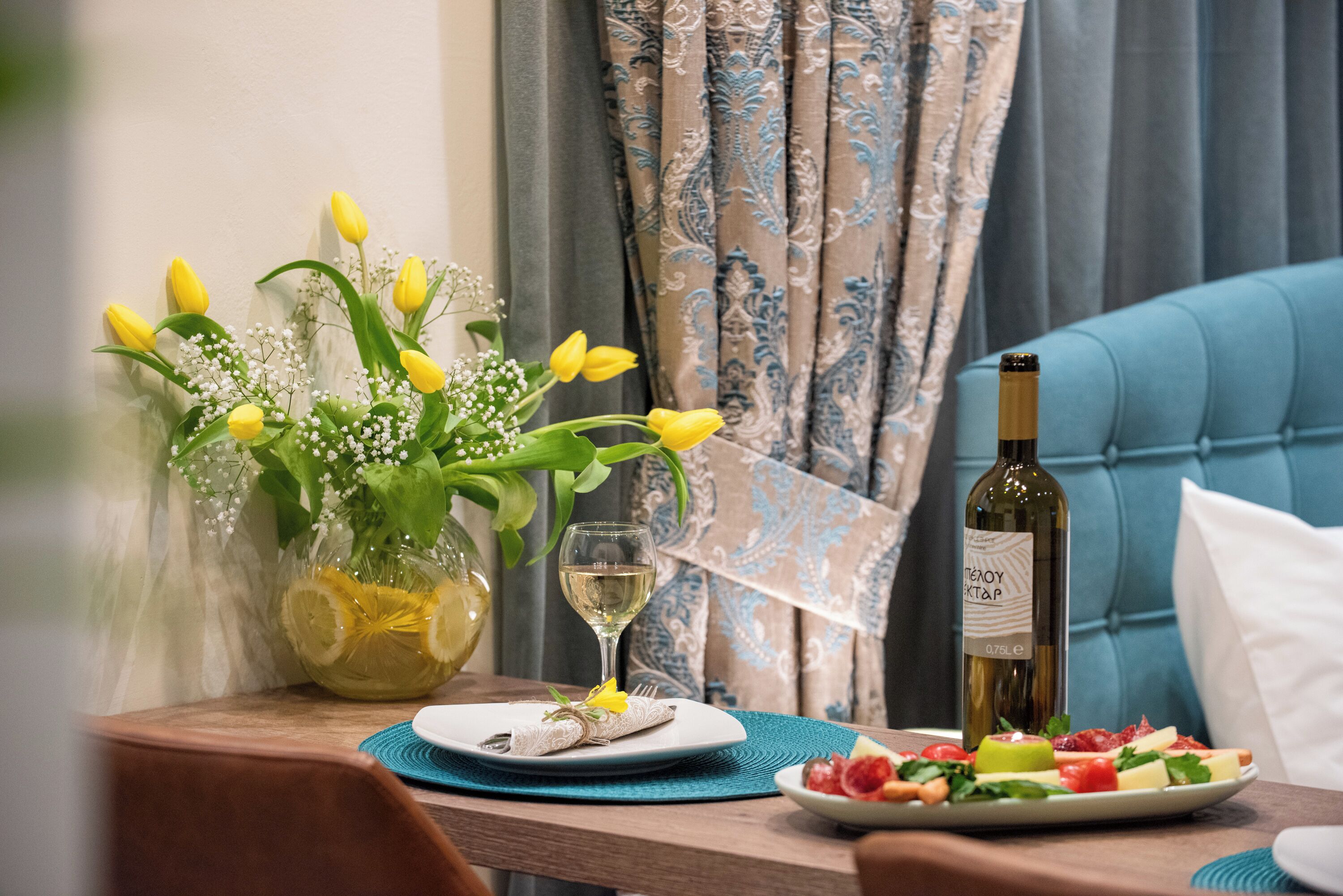 Una mesa de comedor con un plato de comida, una copa de vino blanco y una botella de vino.