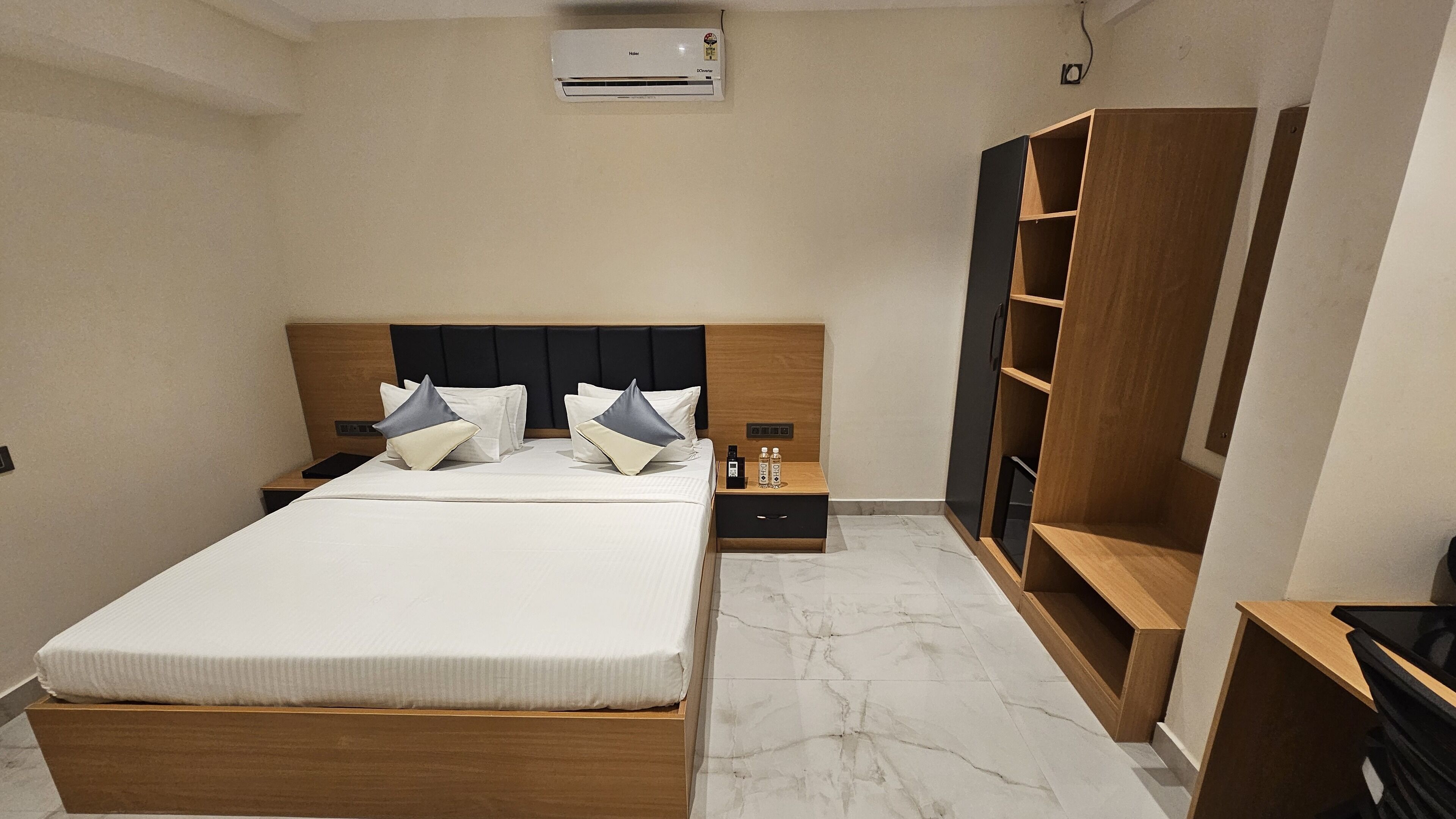 Un dormitorio ordenado con una cama de madera, una mesita de noche, un armario y un equipo de aire acondicionado integrado.