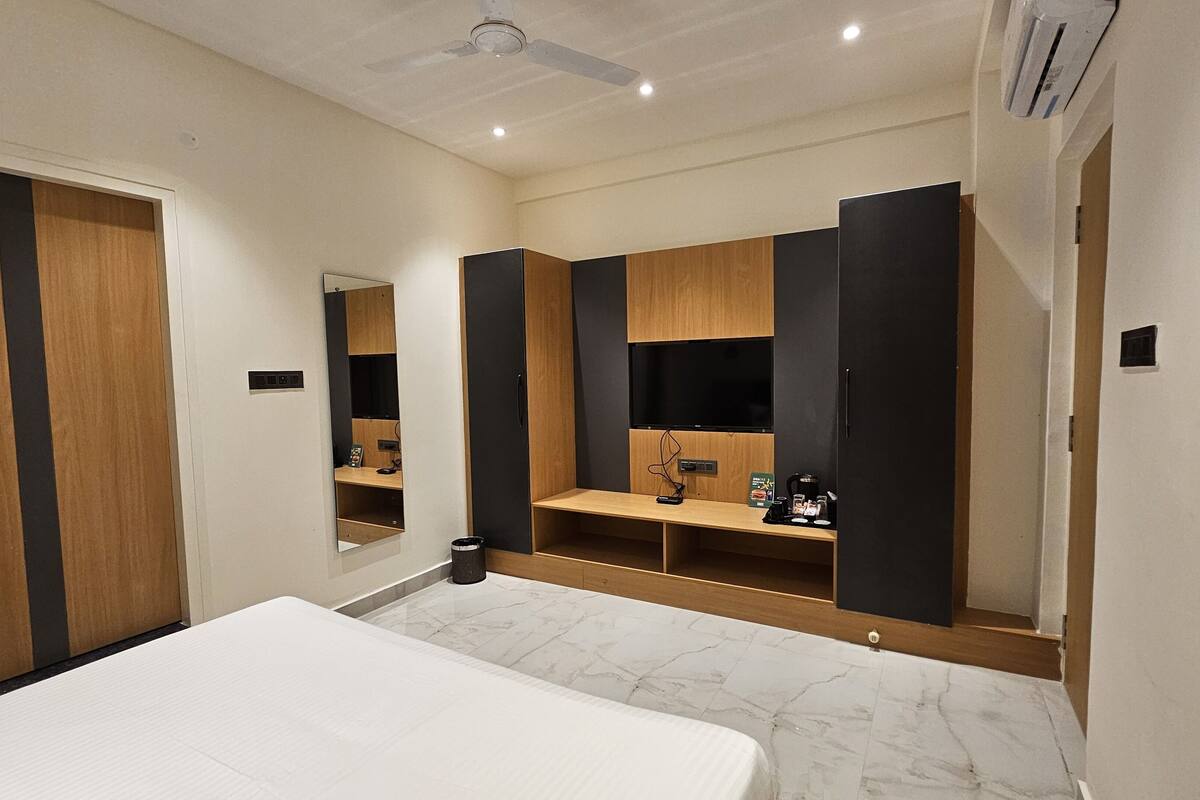 Una habitación de hotel con cama, espejo, armario y repisa con artículos de aseo.