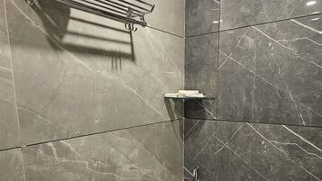 Een moderne badkamer met een wit toilet, een handdoekhouder en een glazen plank.