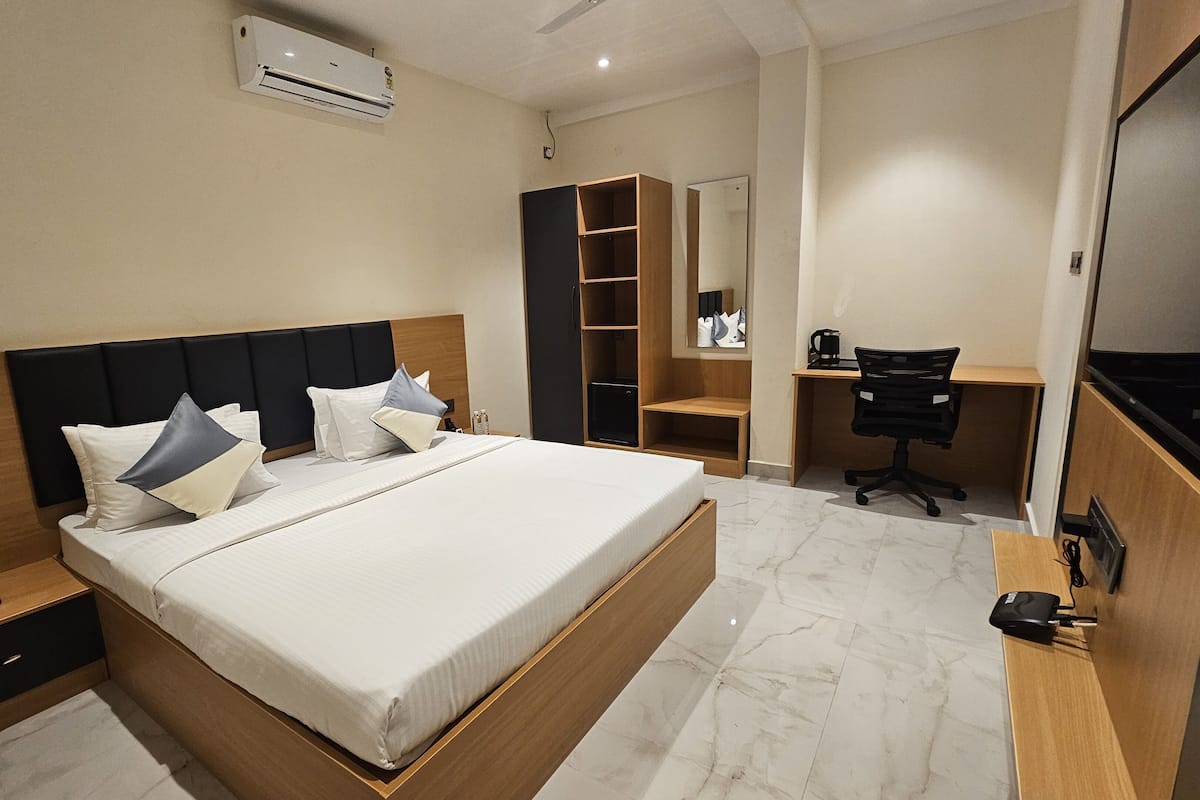 Una habitación de hotel moderna con una cama grande, un escritorio y un armario.