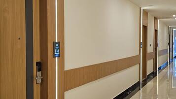 A hotel corridor with wooden paneling, a marble floor, and a sign indicating room number 116.
