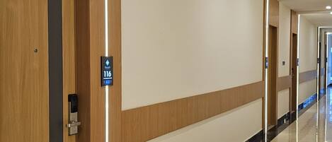 A hotel corridor with wooden paneling, a marble floor, and a sign indicating room number 116.