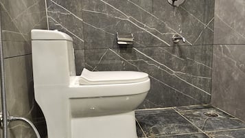 A bathroom with a toilet, a shower, and a glass-enclosed shower area.