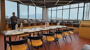 Uma sala de jantar moderna com uma mesa comprida posta para seis pessoas, rodeada por cadeiras amarelas acolchoadas.