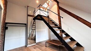A modern interior with a wooden staircase, a sliding door, and a visible ceiling beam. - Exclusive Selection - Luxus Penthouse (Freiburg im Breisgau)