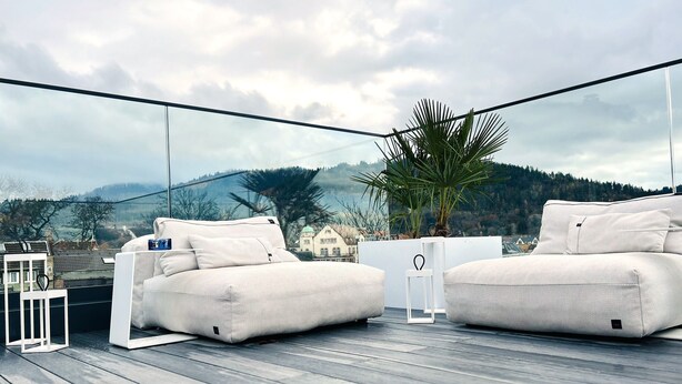 A modern outdoor seating area with two white sofas and a potted plant. - Exclusive Selection - Luxus Penthouse (Freiburg im Breisgau)