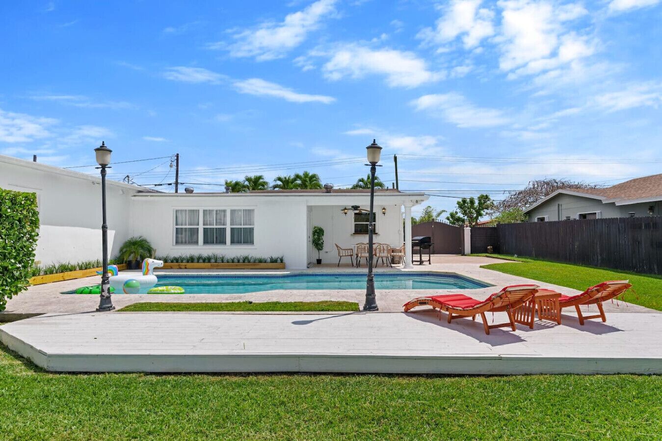 Patio con piscina, mobiliario exterior y una casa blanca.