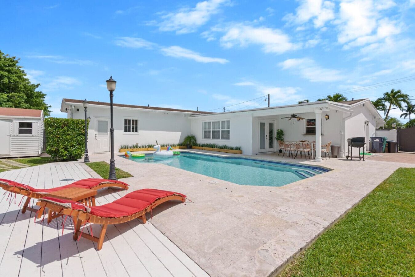 En boligejendom med swimmingpool, en terrasse med liggestole og en overdækket patio.