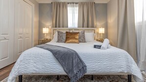 Un lit bien fait, avec une couverture matelassée, deux lampes de chevet, un coussin décoratif et une serviette enroulée sur le côté.