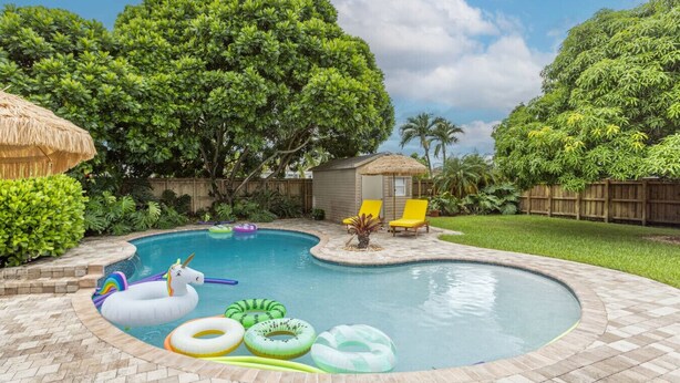 Un giardino con piscina, giochi gonfiabili e una piccola casetta.