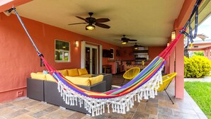 Una veranda riparata con un'amaca, sedute all'aperto e ventilatori a soffitto.