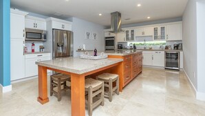 A modern kitchen with white cabinetry, stainless steel appliances, and a central island with stools.