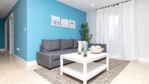 A living room with a grey sofa, a white coffee table, and a blue accent wall.