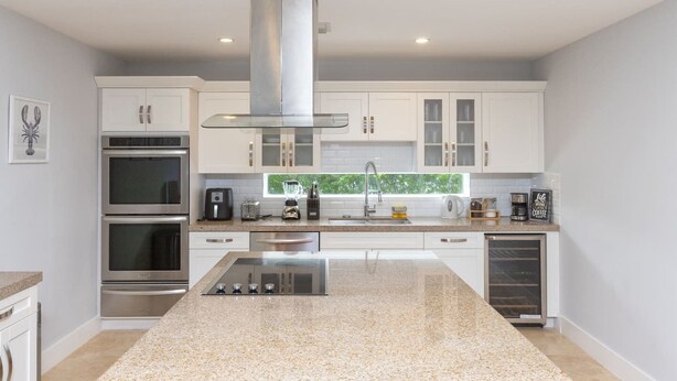 A modern kitchen with white cabinets, stainless steel appliances, and a central island.