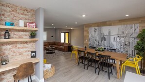 A modern living space with a dining area, a sofa, and a cityscape mural.