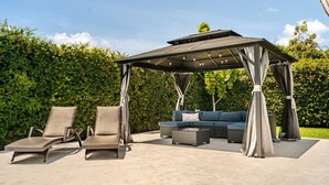 An outdoor patio with a covered seating area, including a sofa and two lounge chairs. - Hawaii Paradise on Miami 4BR Big Pool (Miami)
