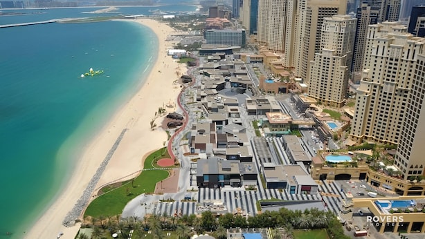 A coastal cityscape with high-rise buildings, a beach, and a marina. - Rovers Beach Hostel JBR (Dubai)