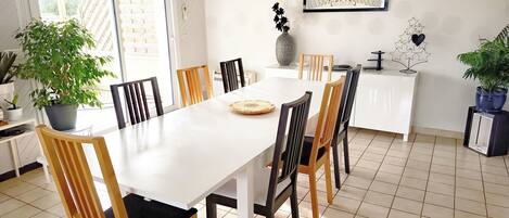 A dining area with a white table, wooden chairs, and a potted plant.