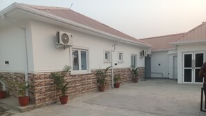 A building with a tiled patio, potted plants, and a brick base. -  Skenyo Hotel & Apartments (Abuja)