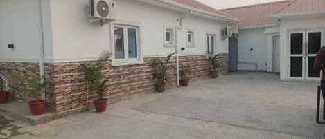 A building with a tiled patio, potted plants, and a brick base.