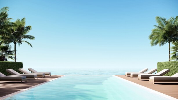 A poolside area with lounge chairs and palm trees, overlooking a calm sea. - Hamakua Hotel (Honomu)