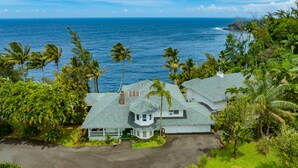 A two-story house with a large front porch and a view of the ocean. - Hamakua Hotel (Honomu)