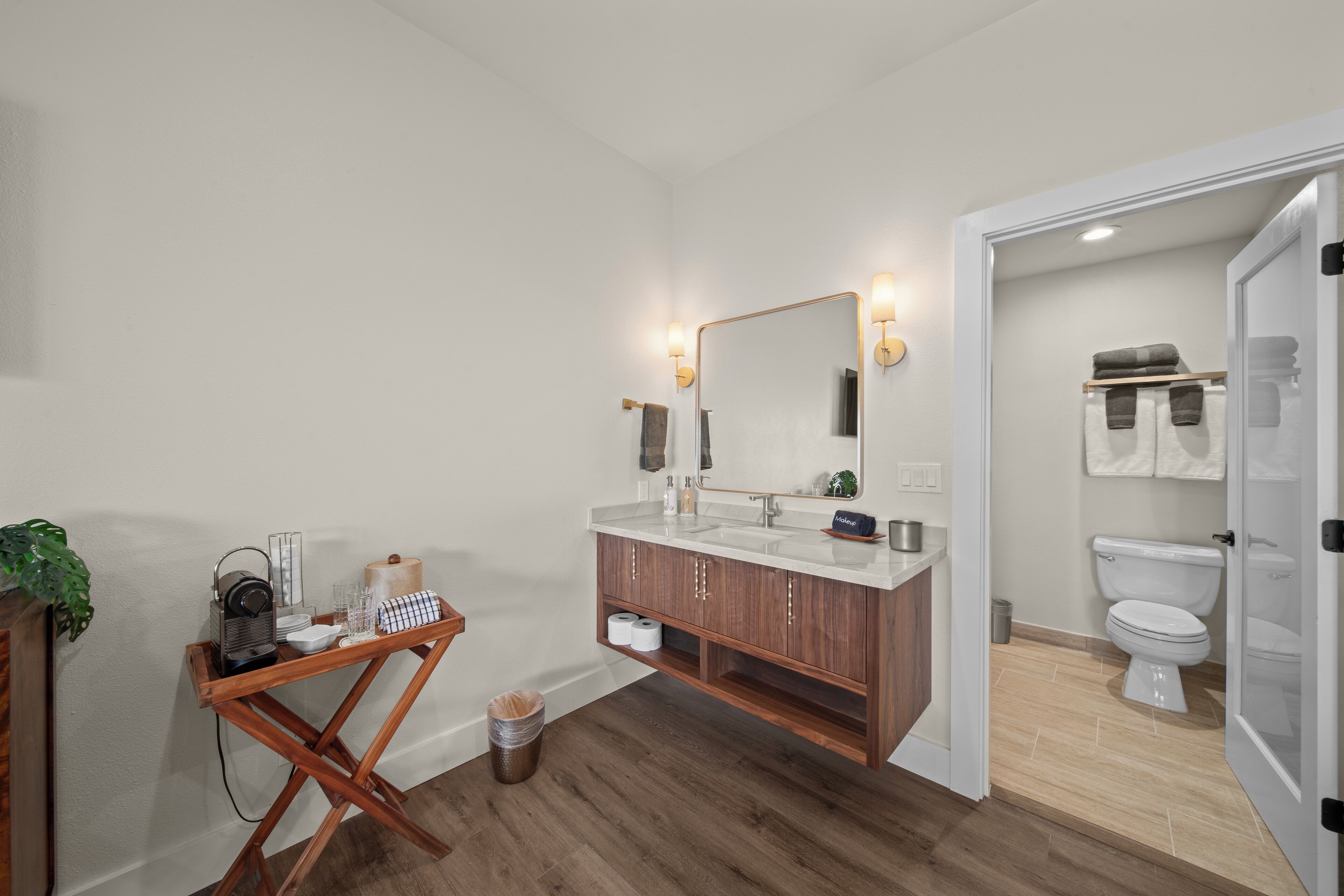 Ein Badezimmer mit einem Holzkosmetikschrank, einem großen Spiegel und einer Toilette.