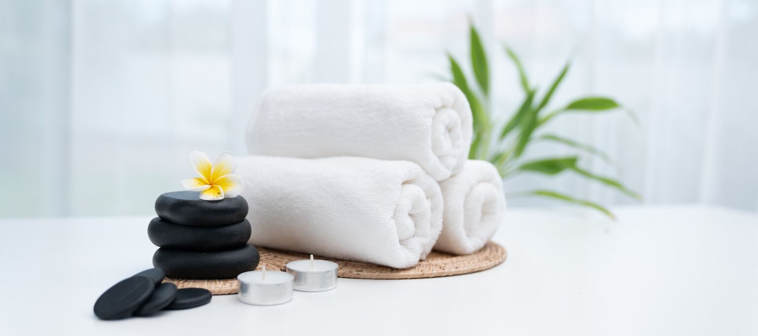 A spa setting with towels, candles, and a flower.