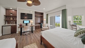 A hotel room with a bed, desk, chair, television, and a balcony with a view. - Hamakua Hotel (Honomu)